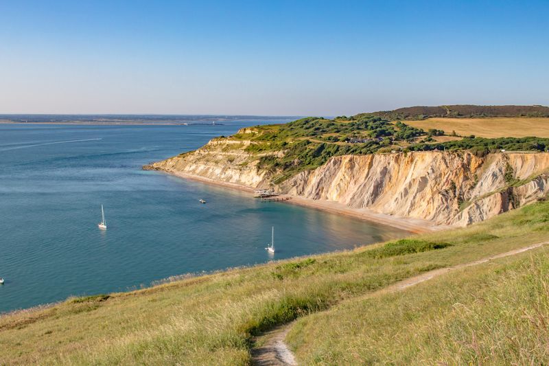 Falaises et petite baie au bord de la mer, sentier côtier au premier plan